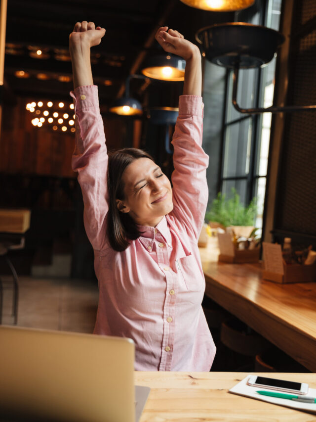 Vertical image of smiling brunette woman sitting by the table